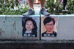 A demonstrator stands above posters featuring Hong Kong Chief Executive Carrie Lam, right, and Hong Kong Secretary for Justice Teresa Cheng in Hong Kong.