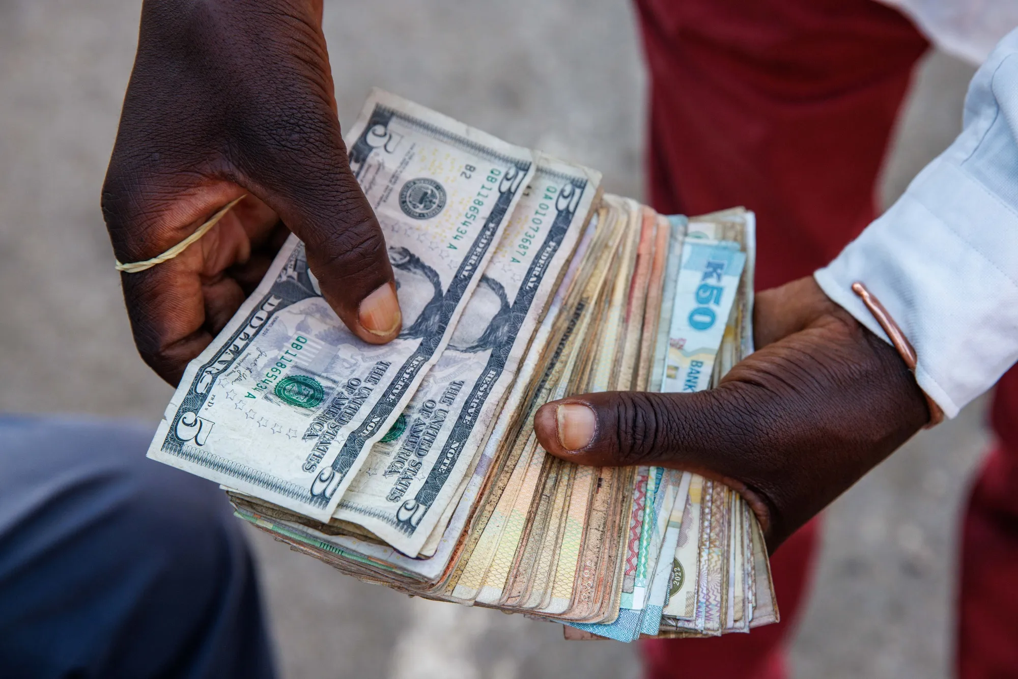 A street currency dealer counts US dollars and Zambian kwacha banknotes in Lusaka.