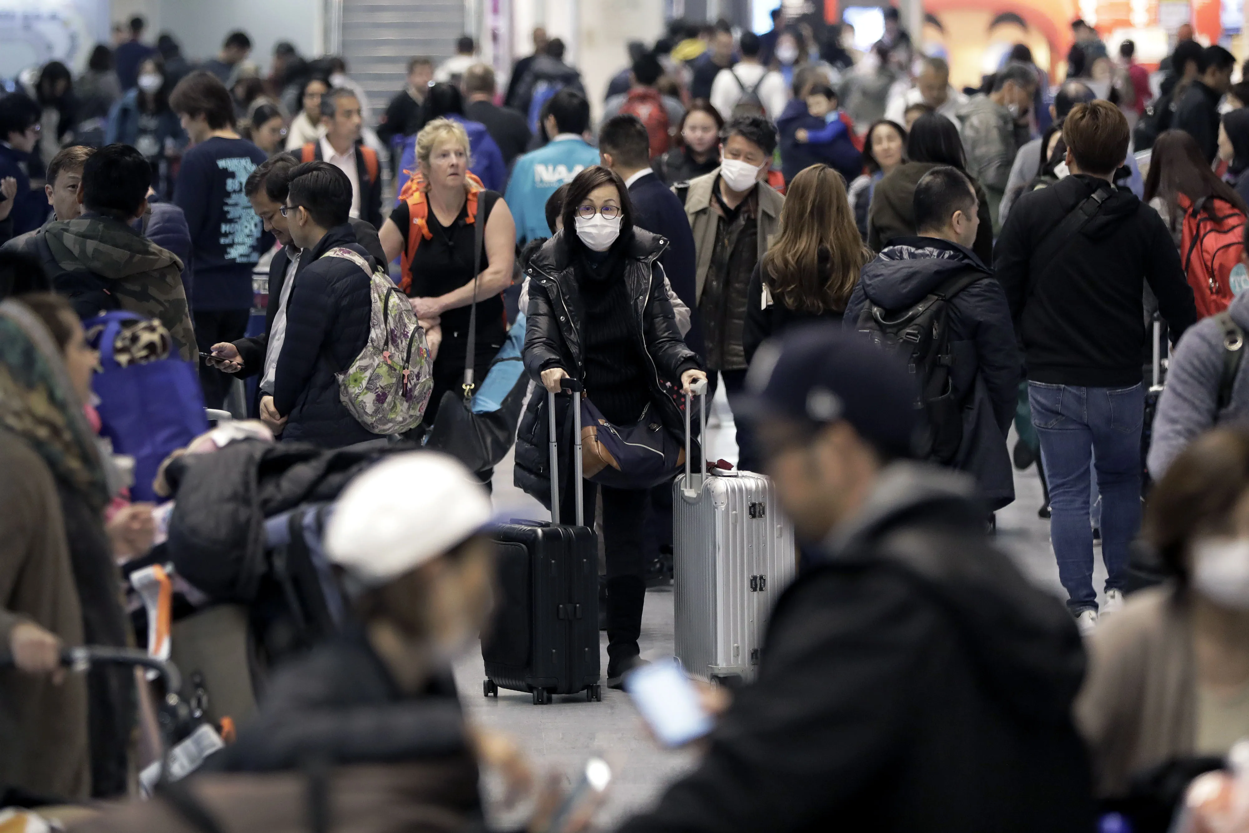 A traveler walks with luggage wearing a protective mask at Narita Airport in Japan, on Jan. 22.
