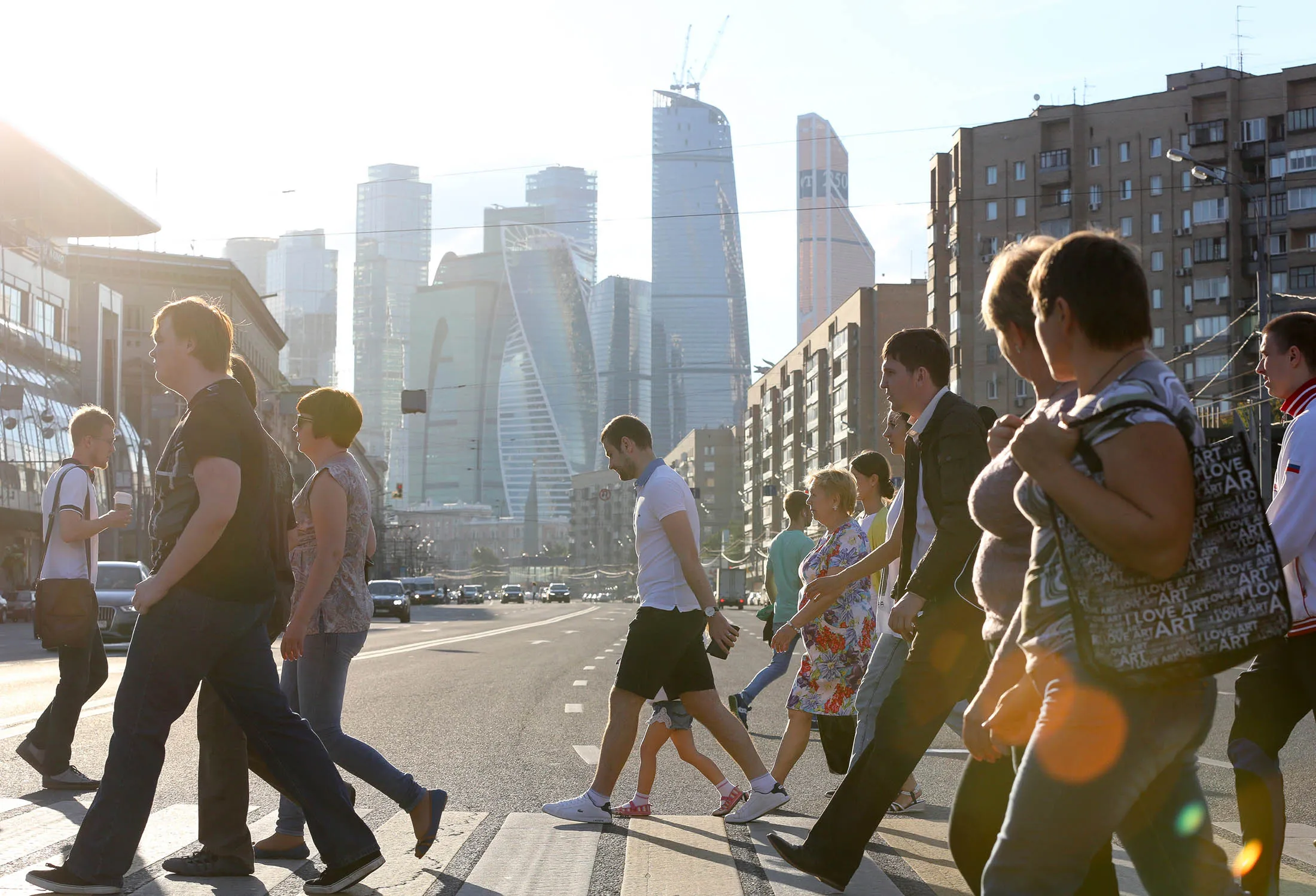 Pedestrians cross a street near the Moscow City business district, center, in Moscow, Russia.
