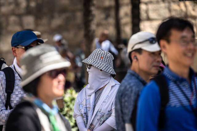 Tourists sometimes fully cover themselves to avoid sunburns. Outside the cathedral during high temperatures in Seville, Spain, on Tuesday, July 4, 2023.