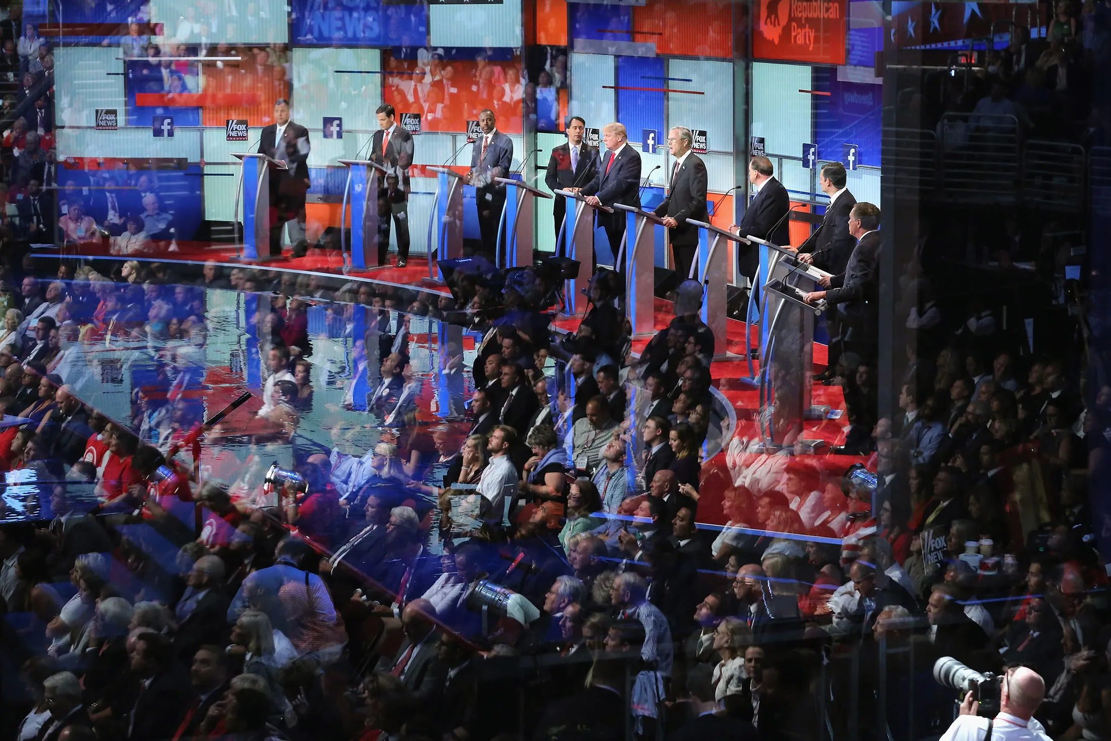Audience members are reflected in a window as Republican presidential candidates debate in Cleveland on Aug. 6.
