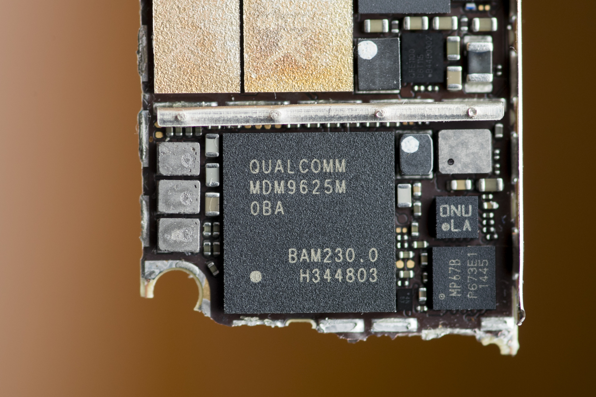 A Qualcomm Inc. baseband modem integrated circuit (IC) chip, bottom, of an Apple Inc. iPhone 6 smartphone is seen in an arranged photograph.