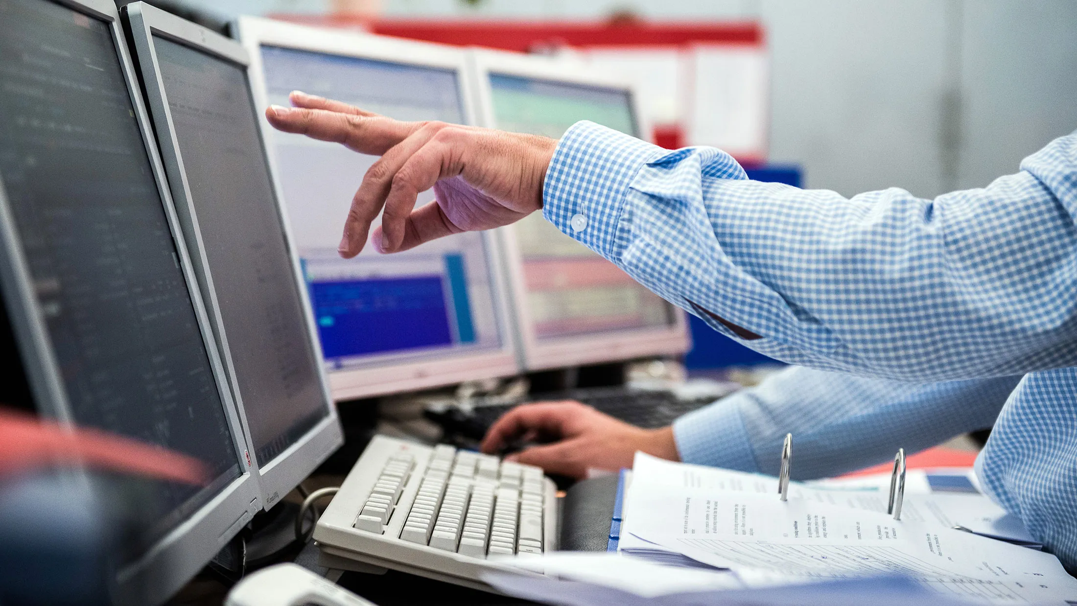 A financial trader points to data displayed on computer screens at a stock exchange in Vienna.
