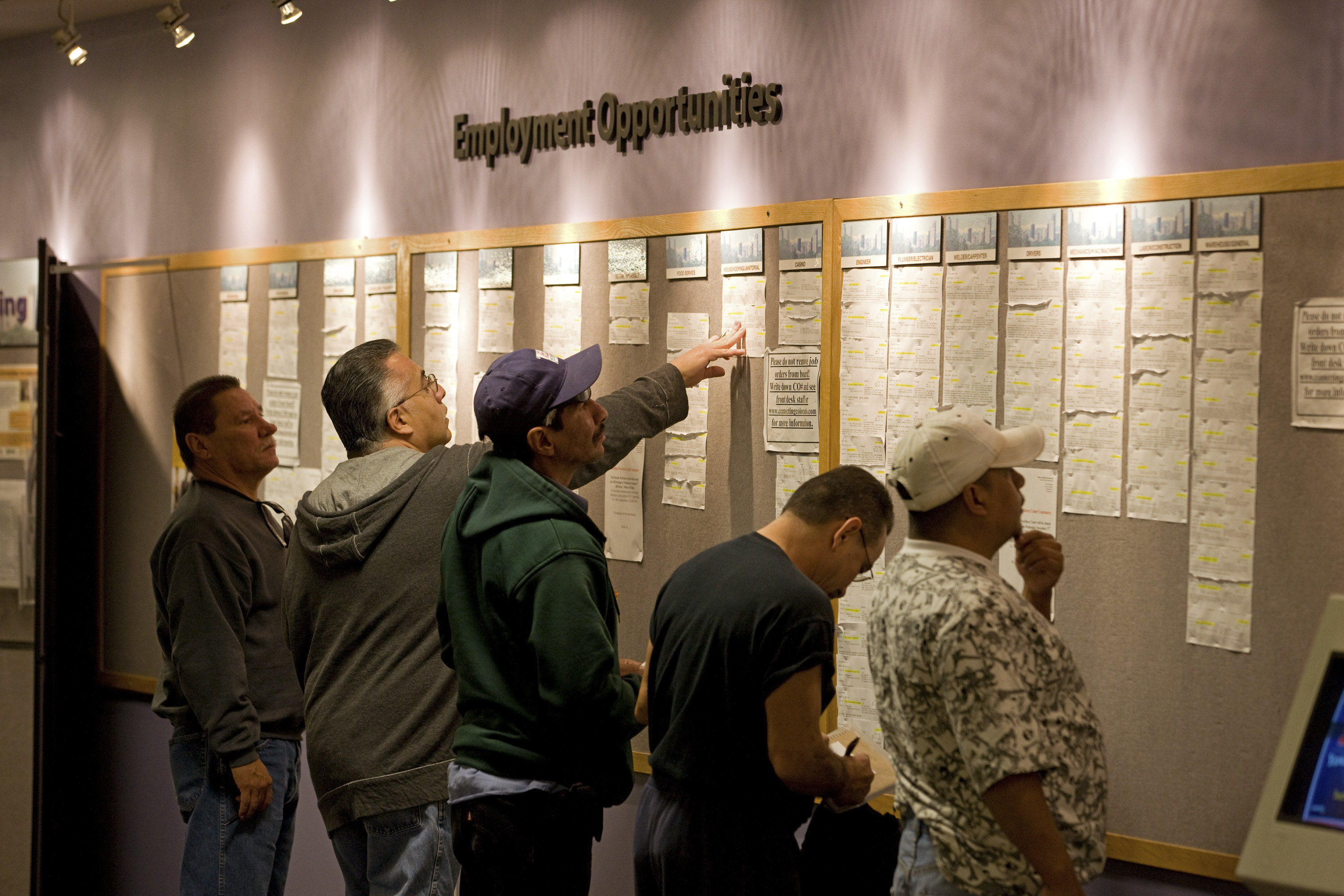 People check the jobs board at a Denver Workforce Center.
