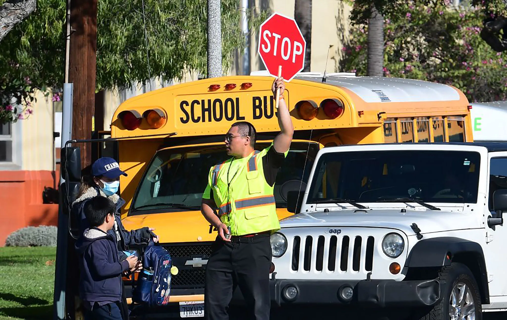 A woman wears a facemask a she picks up a child at a school in Alhambra, California.