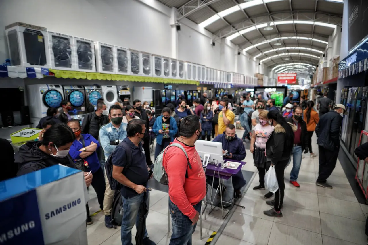 People wearing protective masks gather at an electronics store in Bogota, Colombia, on June 19.