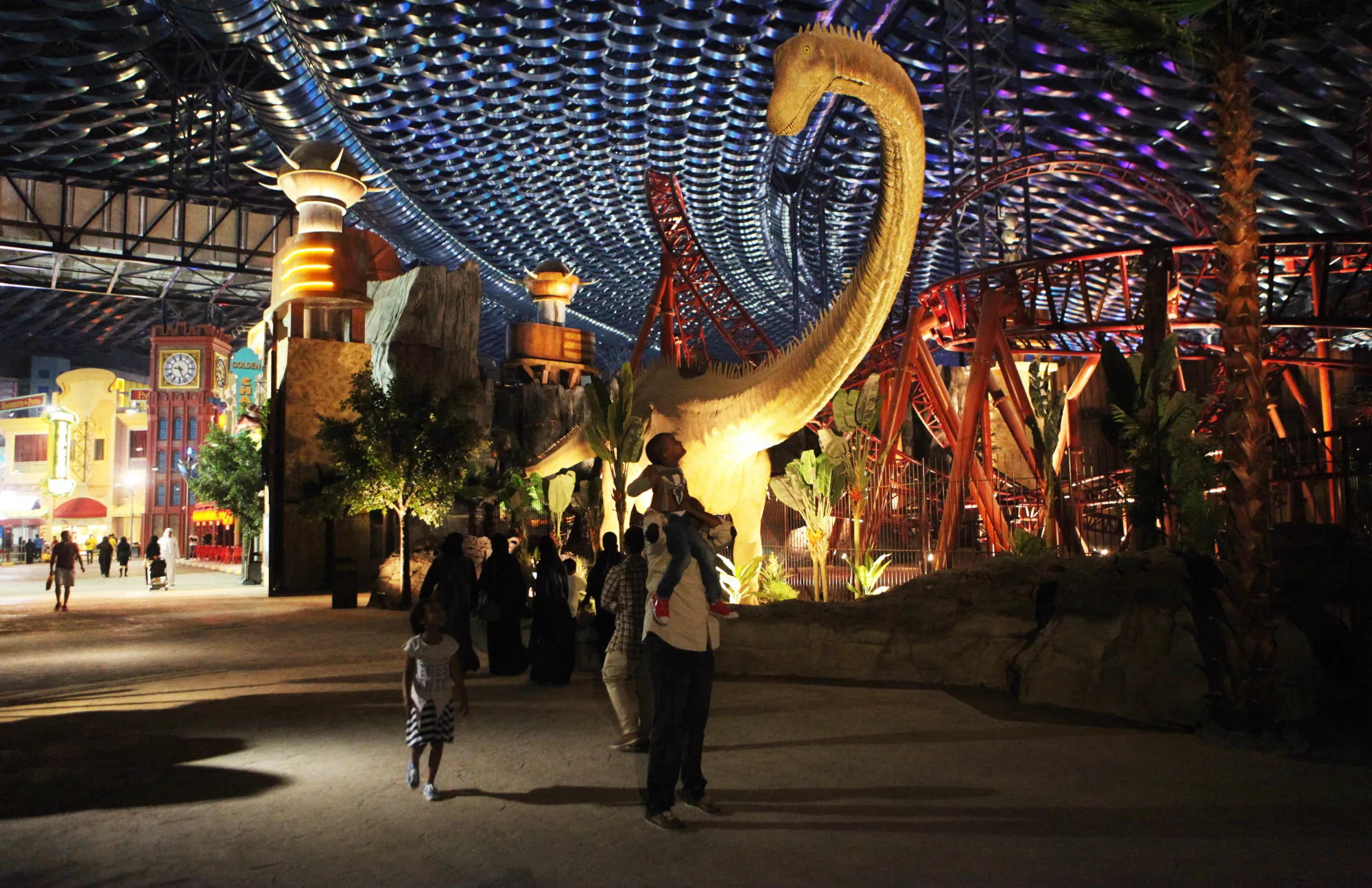 A man puts a small boy on his shoulders to look at an animatronic dinosaur at the IMG Worlds of Adventure amusement park in Dubai, United Arab Emirates, on Wednesday, Aug. 31, 2016. The IMG Worlds of Adventure indoor theme park opened Wednesday in Dubai, hoping to draw thrill seekers to its air-conditioned confines.
