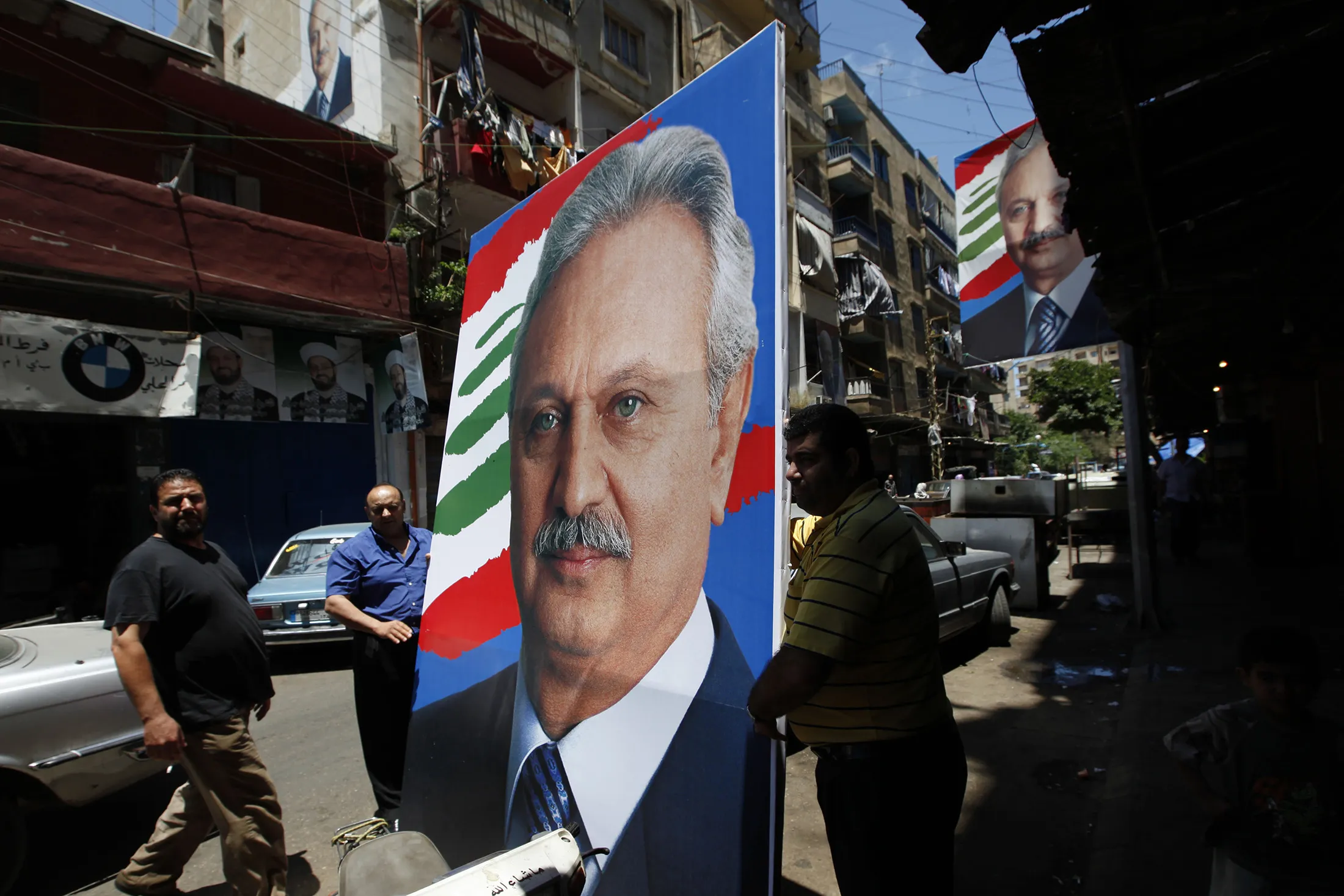 Lebanese electoral office workers set up a poster with a picture of Mohammed al Safadi in Lebanon.