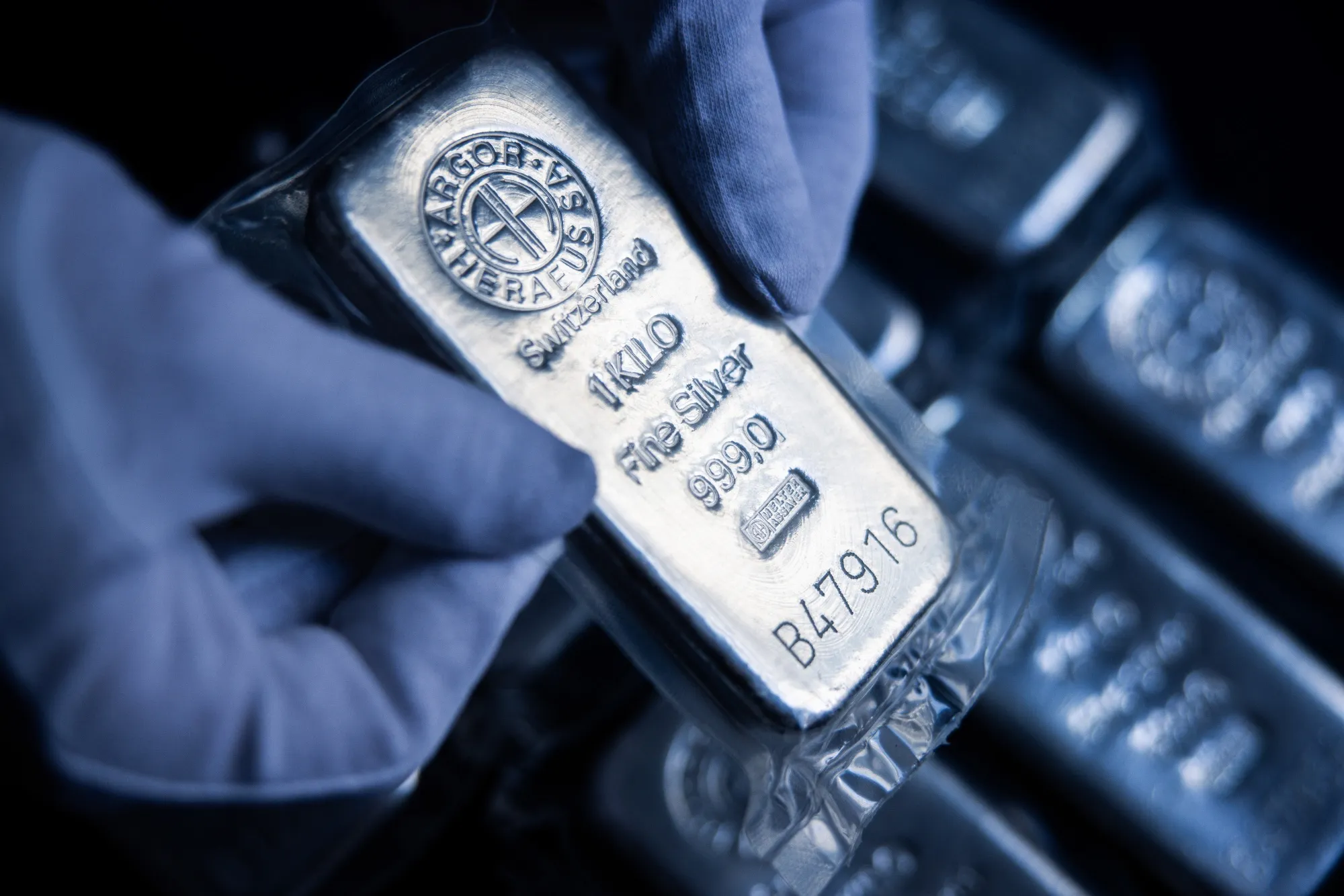 An attendant holds a one kilogram silver bar.