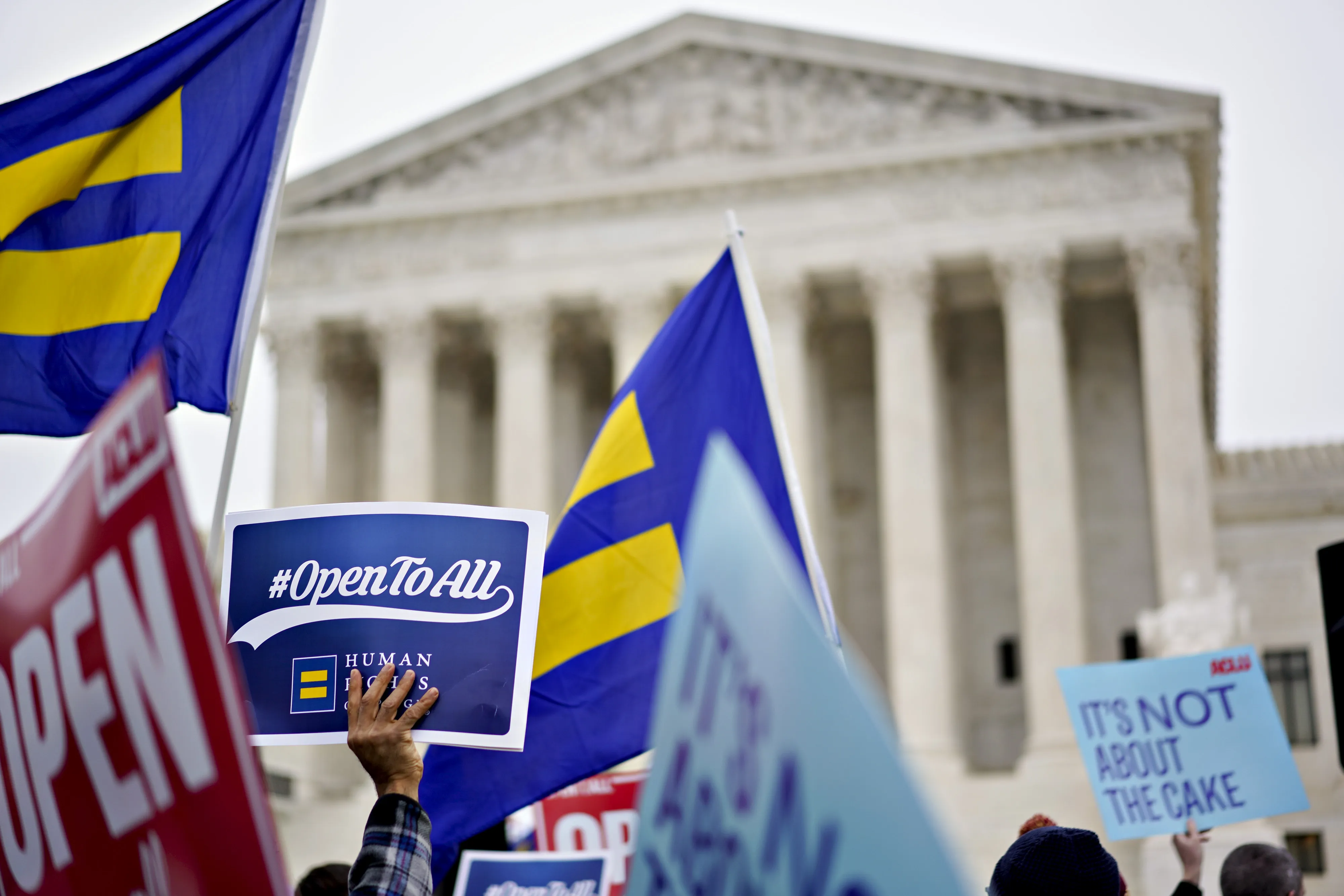 Demonstrators hold signs and flags in support of David Mullins and husband Charlie Craig outside the U.S. Supreme Court during arguments in the Masterpiece Cakeshop v. Colorado Civil Rights Commission case in Washington, D.C., U.S., on Tuesday, Dec. 5, 2017.&nbsp;