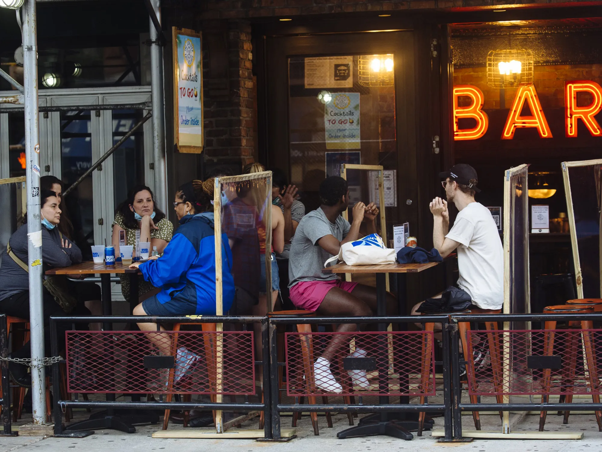 People sit outside a bar in the East Village neighborhood of New York on July 6.