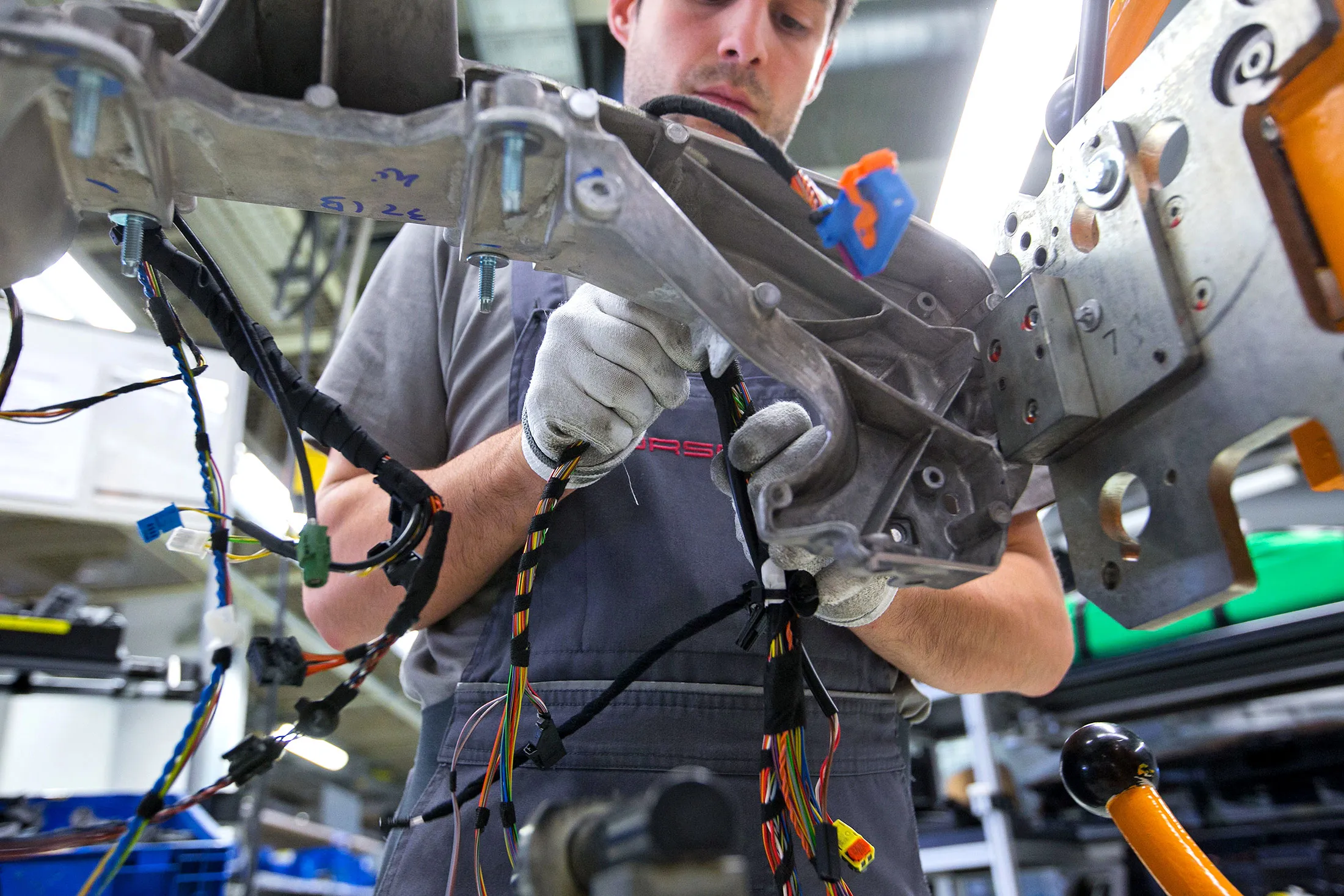 An employee secures electrical cables into a Porsche 911 in Stuttgart, Germany.
