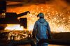 An employee wears protective clothing as sparks fly from a blast furnace at ThyssenKrupp AG's steel plant in Duisburg, Germany.