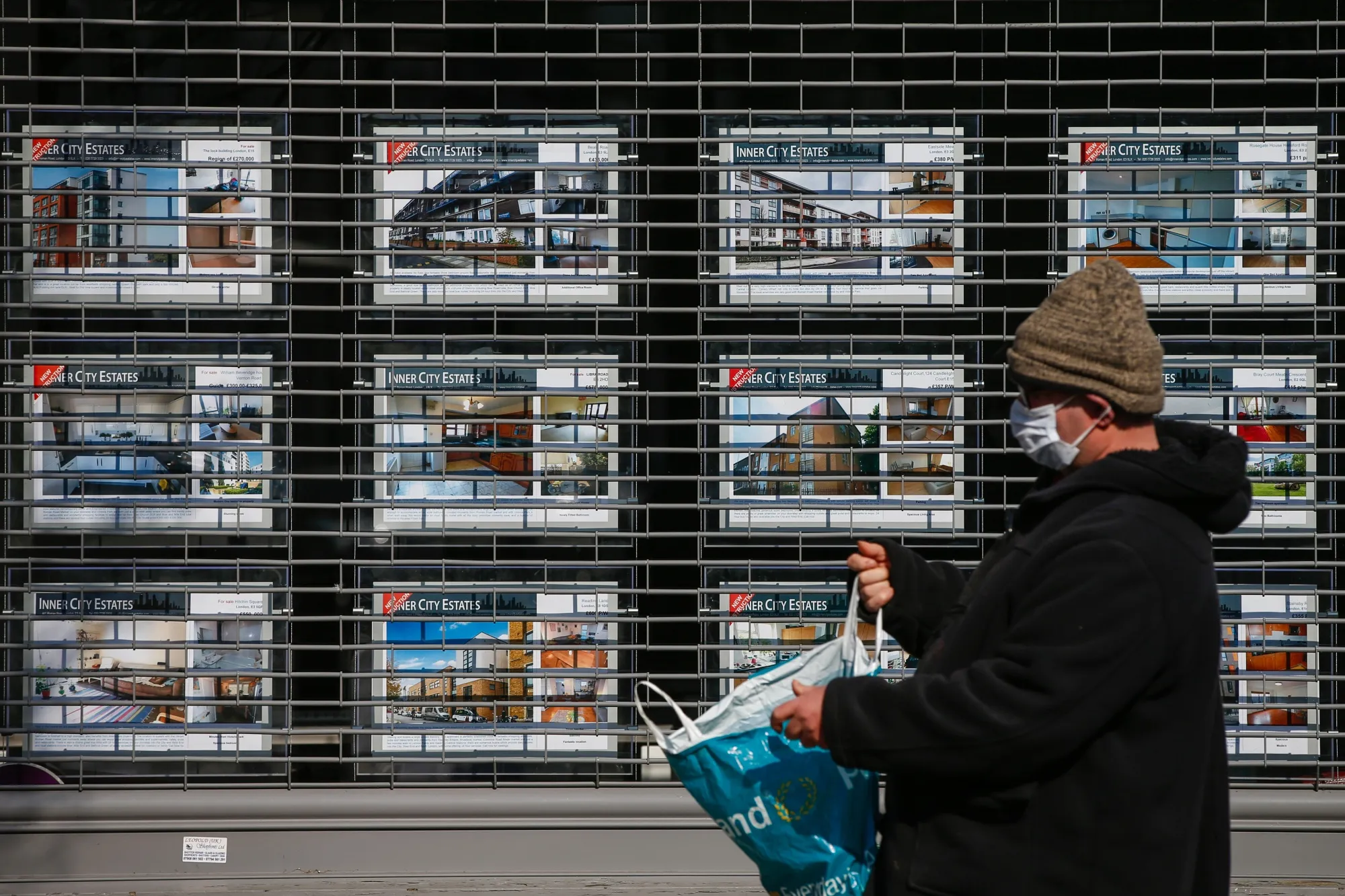 A pedestrian wearing a protective face mask walks past a shuttered estate agents' branch in London, on March 27.