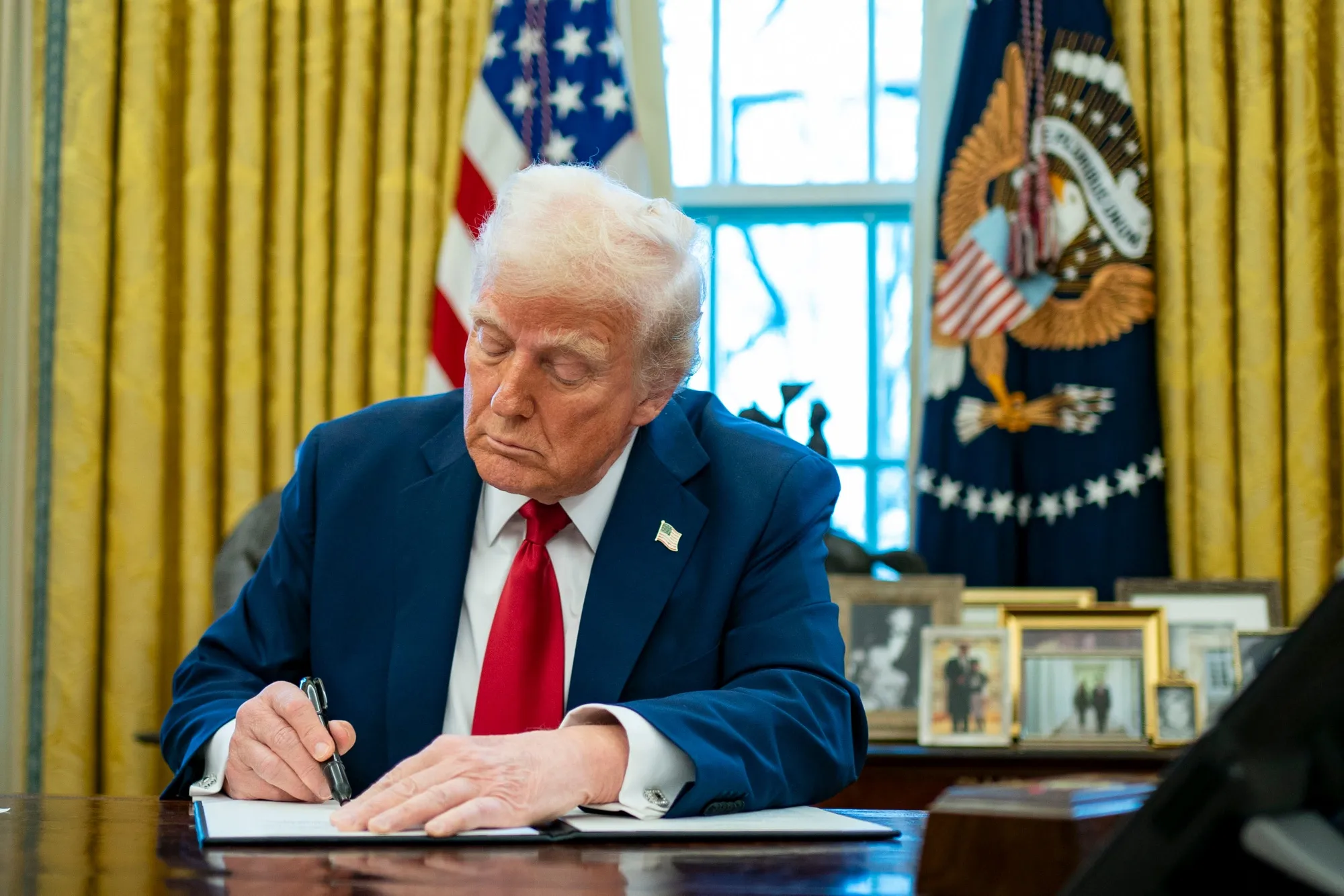 Donald Trump signs an executive order in the Oval Office of the White House in Washington, DC, on Jan. 30.