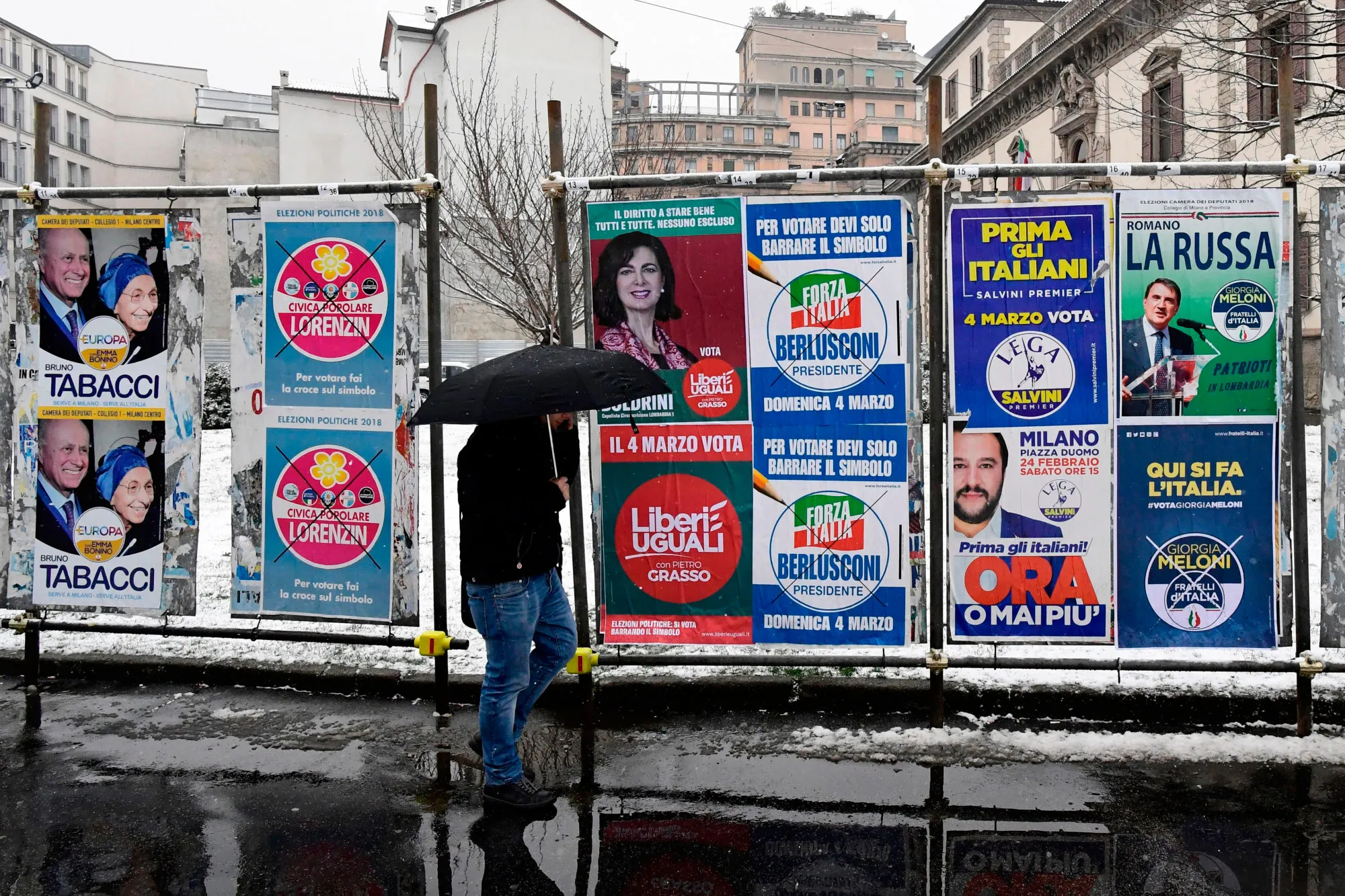 A pedestrian passes in front of election hoardings in Milan on March 1.