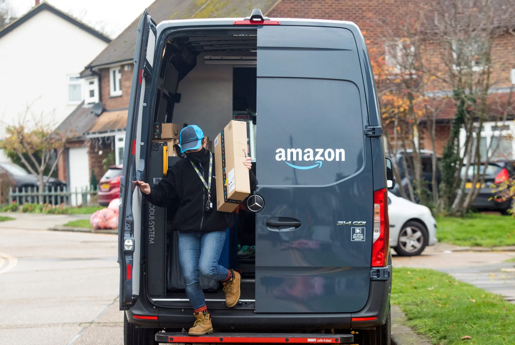 An Amazon.com Inc. delivery driver carries a package from a delivery van.
