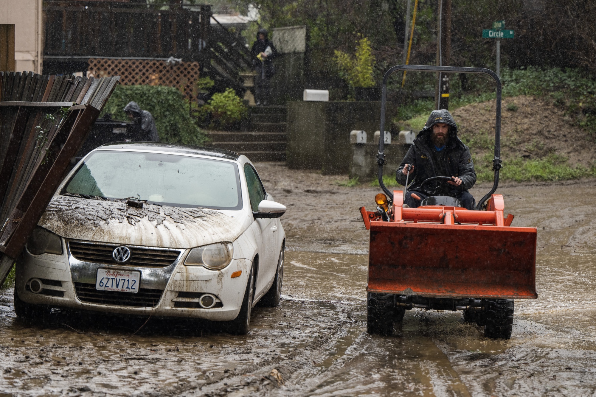 A resident drives a tractor to clear mud after flooding in Felton Grove neighborhood of Felton, California, on Jan. 11.