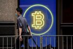 A commuter passes a digital display of cryptocurrency Bitcoin in Central district in Hong Kong.