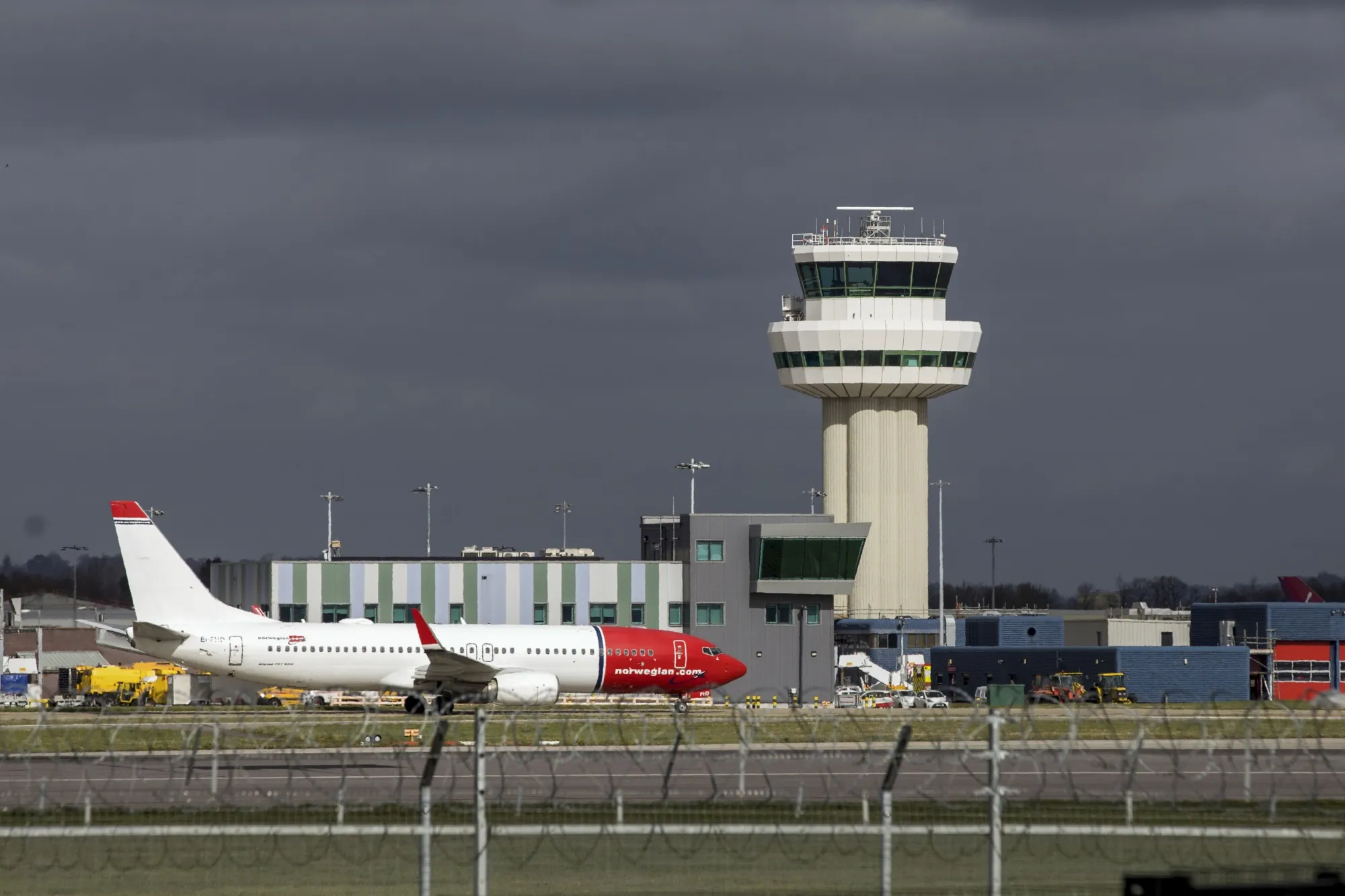 A passenger aircraft, operated by Norwegian Air Shuttle ASA, taxis along the runway in view of the control tower at Gatwick Airport in Crawley.