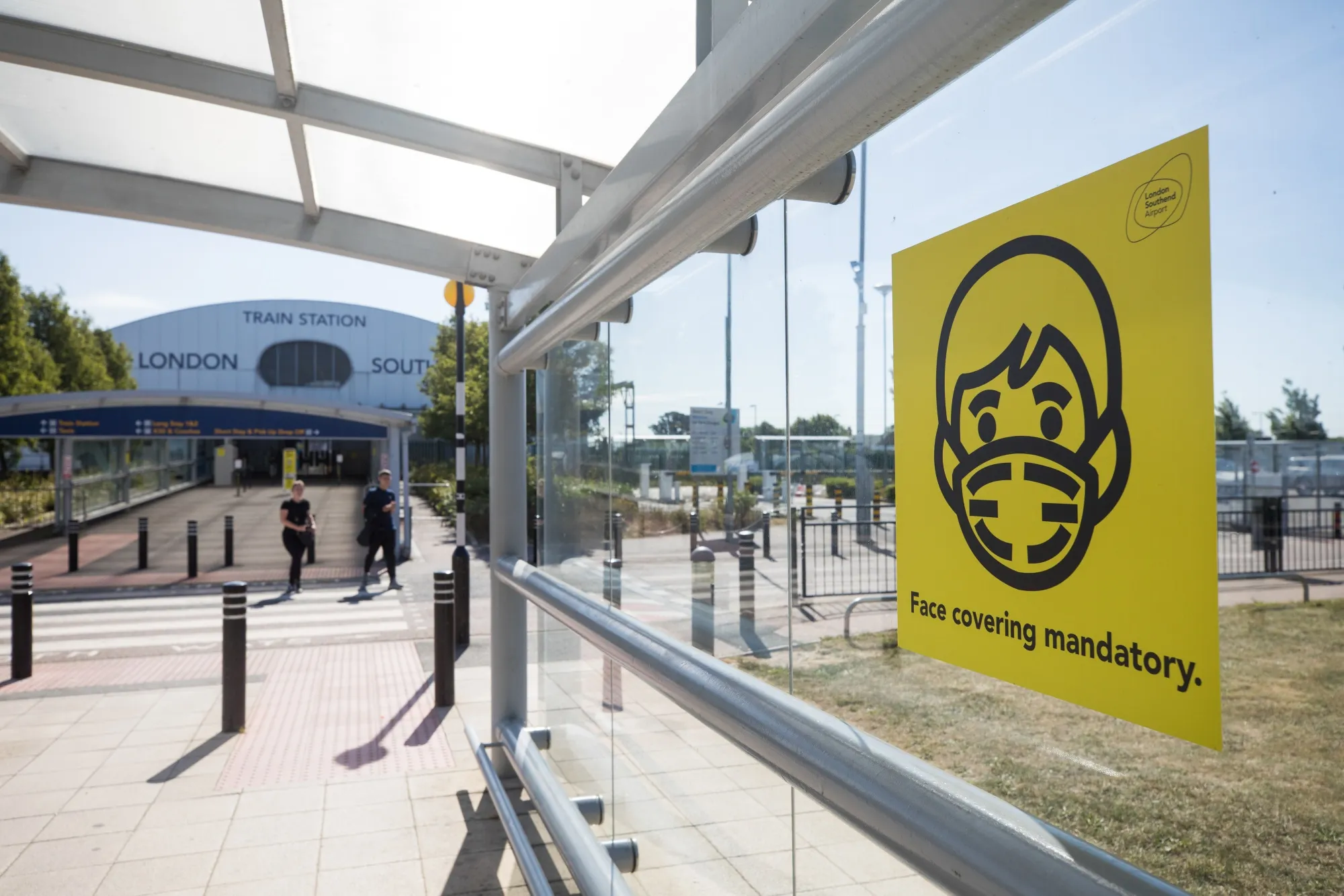A public health notice reminding people to wear face coverings stands at the entrance to London Southend Airport.