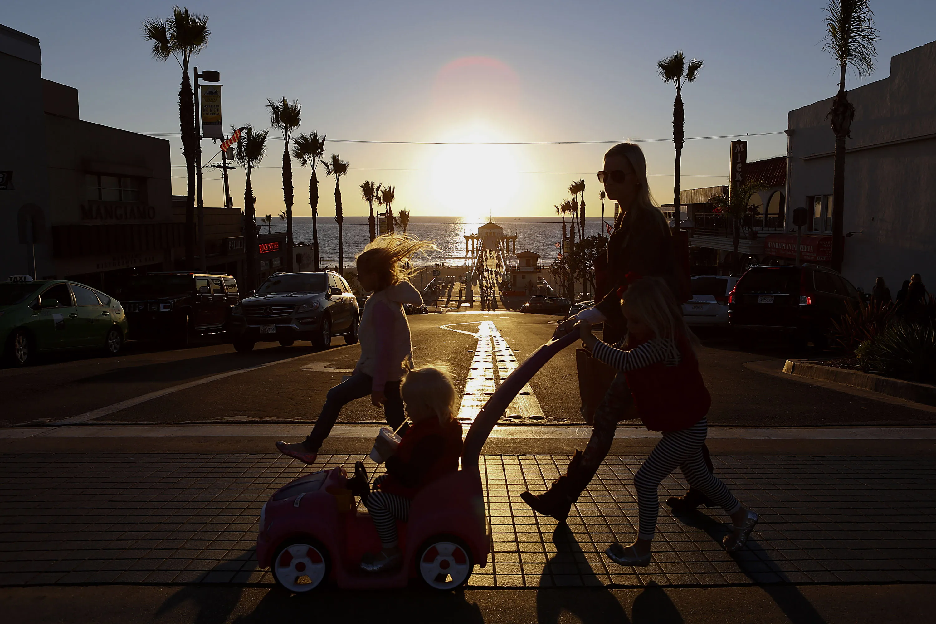 A woman and three children cross the street by the pier in Manhattan Beach, California.
