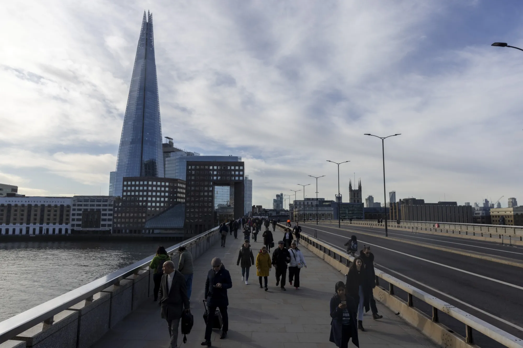 Morning commuters cross London Bridge in the City of London, UK.
