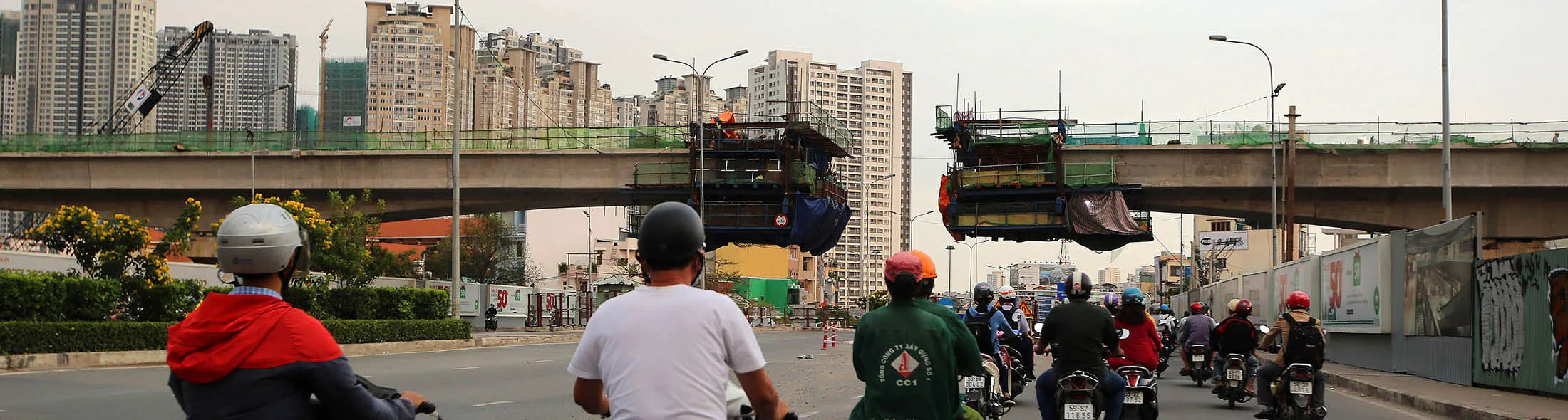 Motorcyclists travel along a road as construction continues on a bridge in Ho Chi Minh City, Vietnam.
