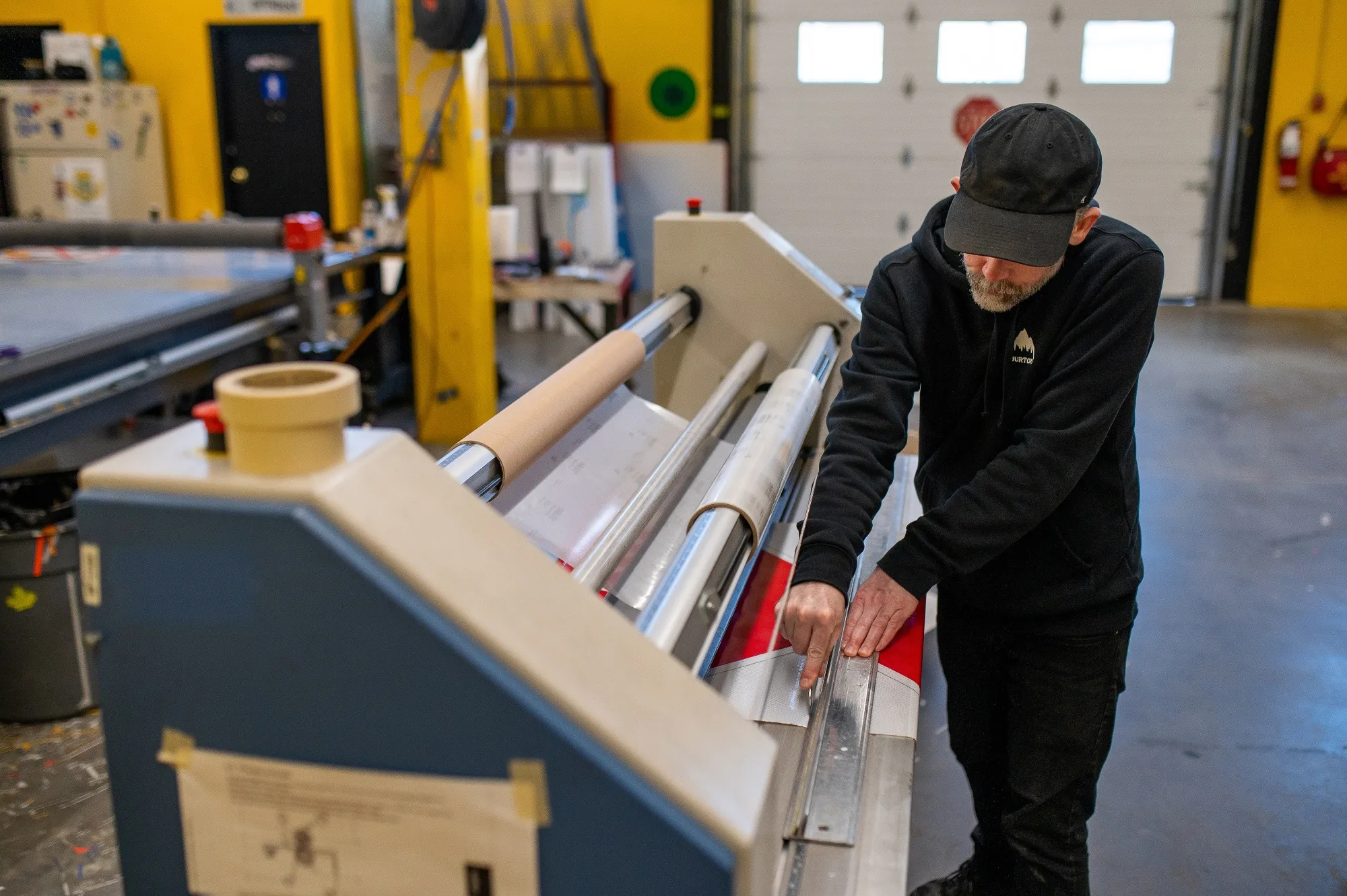 A worker laminates signs at manufacturing shop in Langford, British Columbia on May 18.