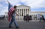 A pedestrians carries an American flag near abortion rights demonstrators outside the US Supreme Court in Washington, D.C., on&nbsp;May 11.
