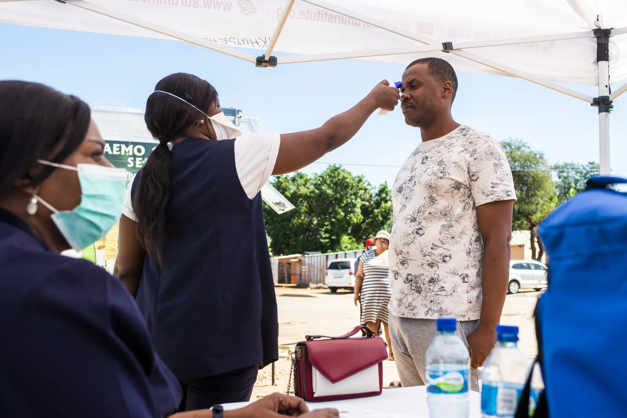 A medical worker checks the temperature of a local resident during a regional health screening program in Rustenburg, South Africa.