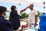 A medical worker checks the temperature of a local resident during a regional health screening program in Rustenburg, South Africa.