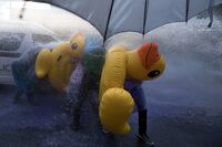 Protesters take cover with inflatable ducks and umbrellas as police use water cannons in Bangkok on Tuesday.