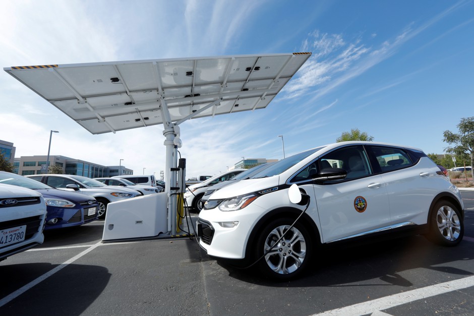 A small fleet of electric Chevrolet Bolts charge under a solar panel charging system in San Diego, California.