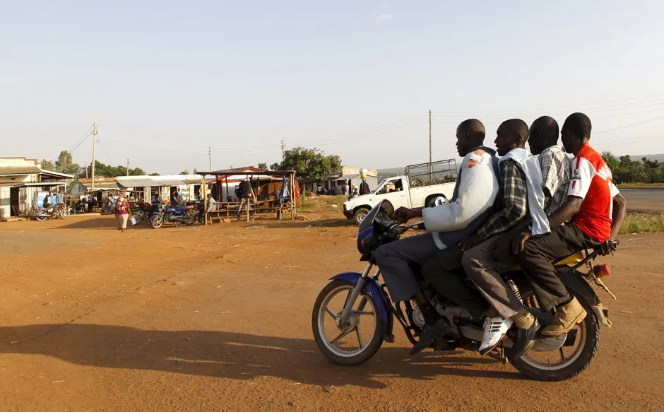 A motorbike taxi carries three passengers past a trading center in the village of Kogelo, west of Kenya's capital of Nairobi.