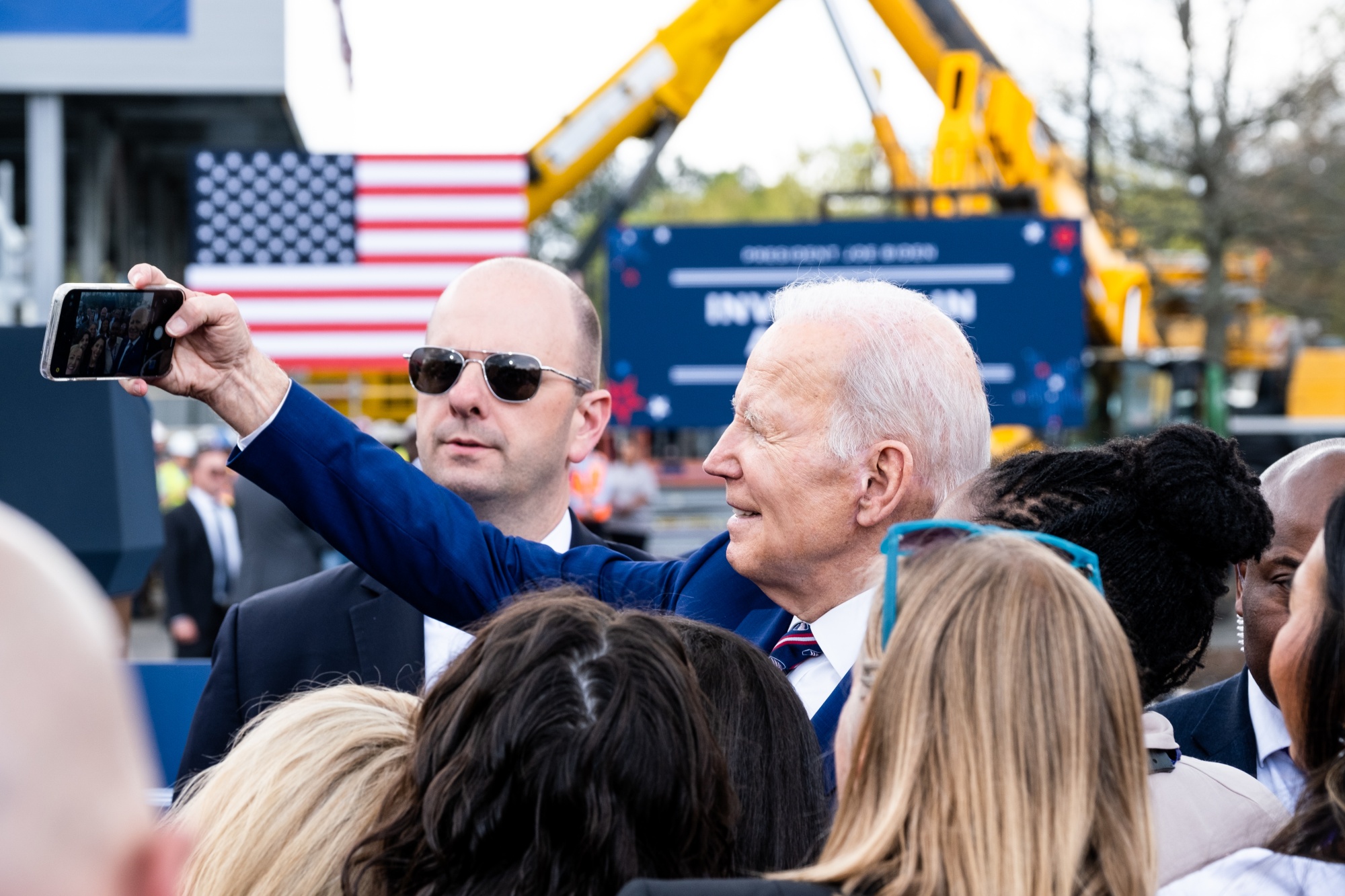US President Joe Biden poses for selfie photographs with attendees at Wolfspeed Inc. in Durham, North Carolina, US, on Tuesday, March 28, 2023. Wolfspeed, a manufacturer of semiconductors and chip components, has announced a $5 billion investment that will create 1,800 new jobs, according to a White House official.