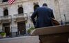 A man sits on a bench in front of the New York Stock Exchange (NYSE) in New York, U.S..