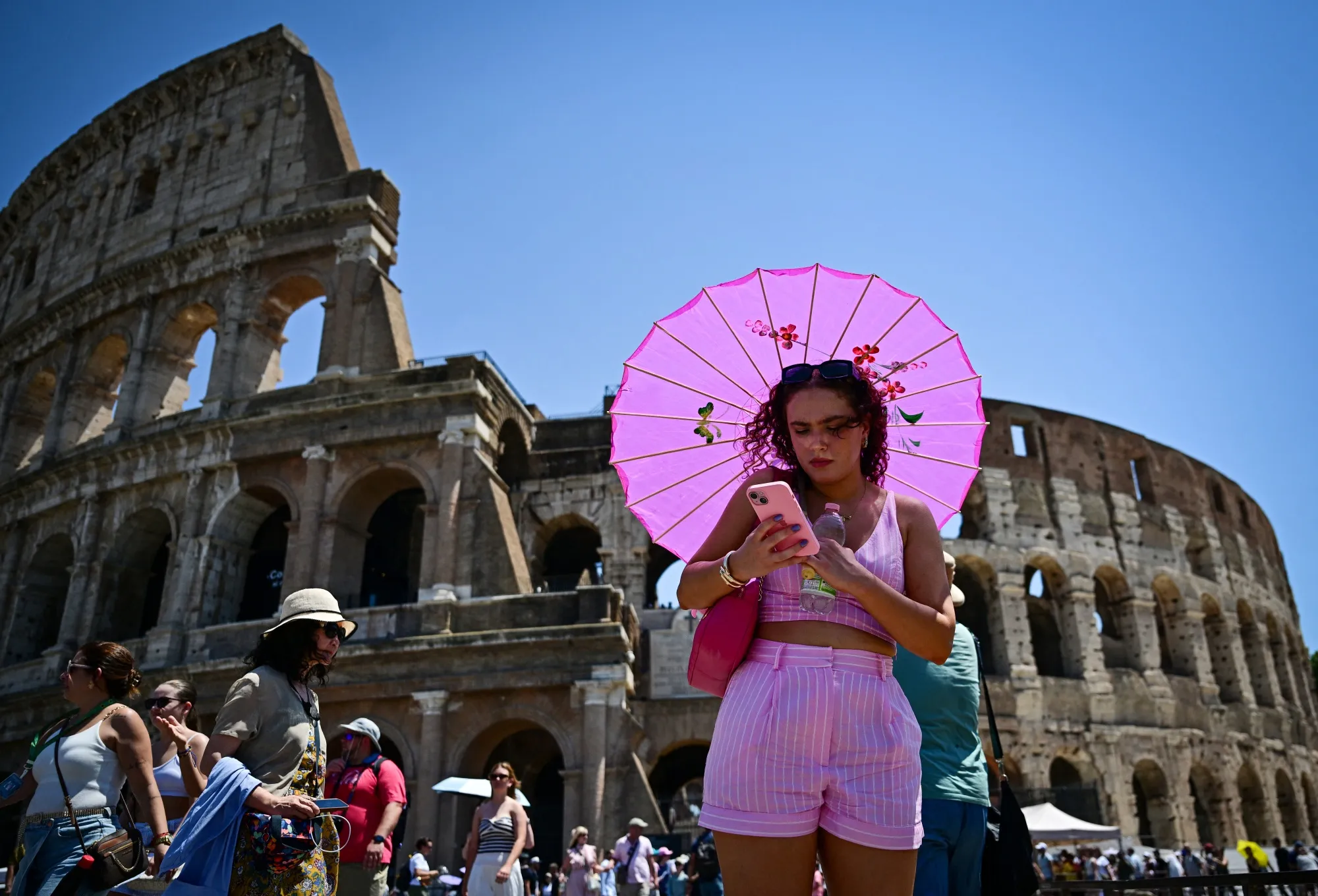 A woman holds an umbrella to protect herself from the sun on a hot summer day in Rome on July 1.