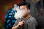 A person exhales vapor while using an electronic cigarette device.