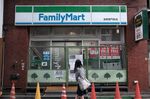 A pedestrian walks past a closed FamilyMart Co. convenience store in the Asakusa district of Tokyo, Japan.