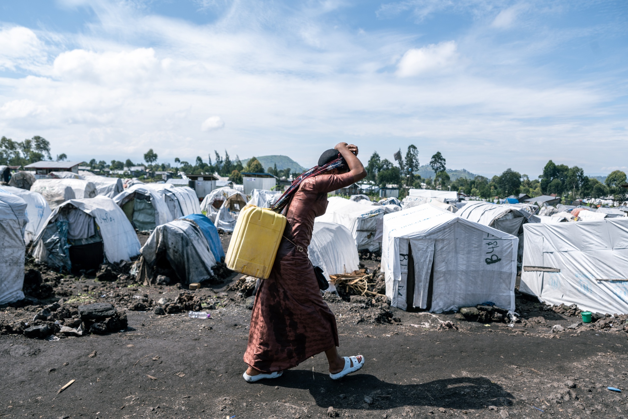 An internally displaced person carries water collected from a standpipe to her shelter in the Shabindu camp, where displaced people from Masisi territory take refuge following clashes between M23 rebels and the Congolese army, in North Kivu province, Democratic Republic of Congo, on Tuesday, April 9, 2024. Rwandan meddling is deepening Congo's deadly conflict, which intensified in late 2021 and involves dozens of armed groups, long-running ethnic tensions and at least five national armies, has now reached a peak not seen in at least a decade. Photographer: Arlette Bashizi/Bloomberg 
