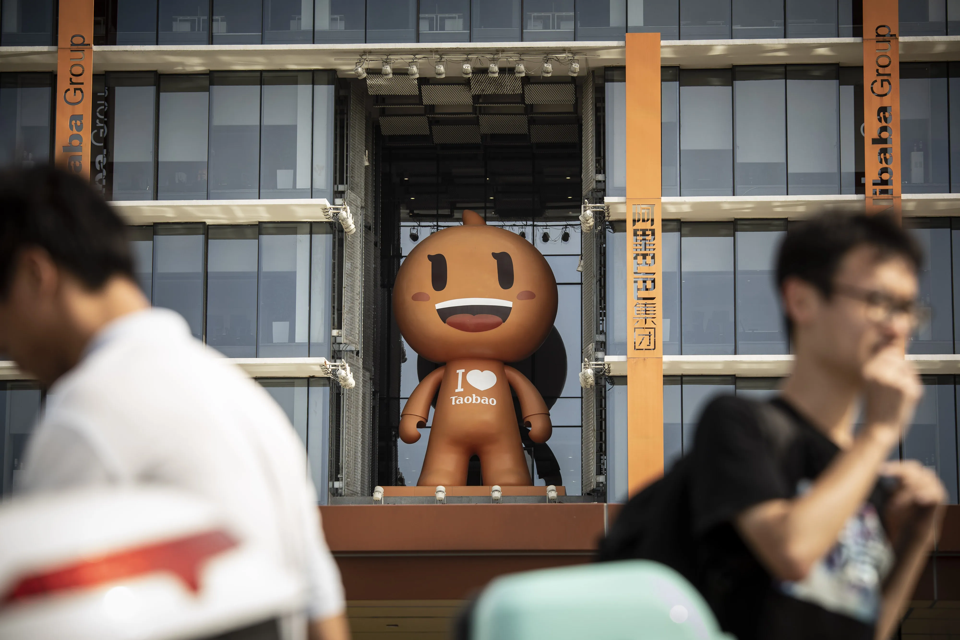 People walk past the mascot for the Taobao e-commerce platform&nbsp;at the Alibaba&nbsp;headquarters in Hangzhou, China.