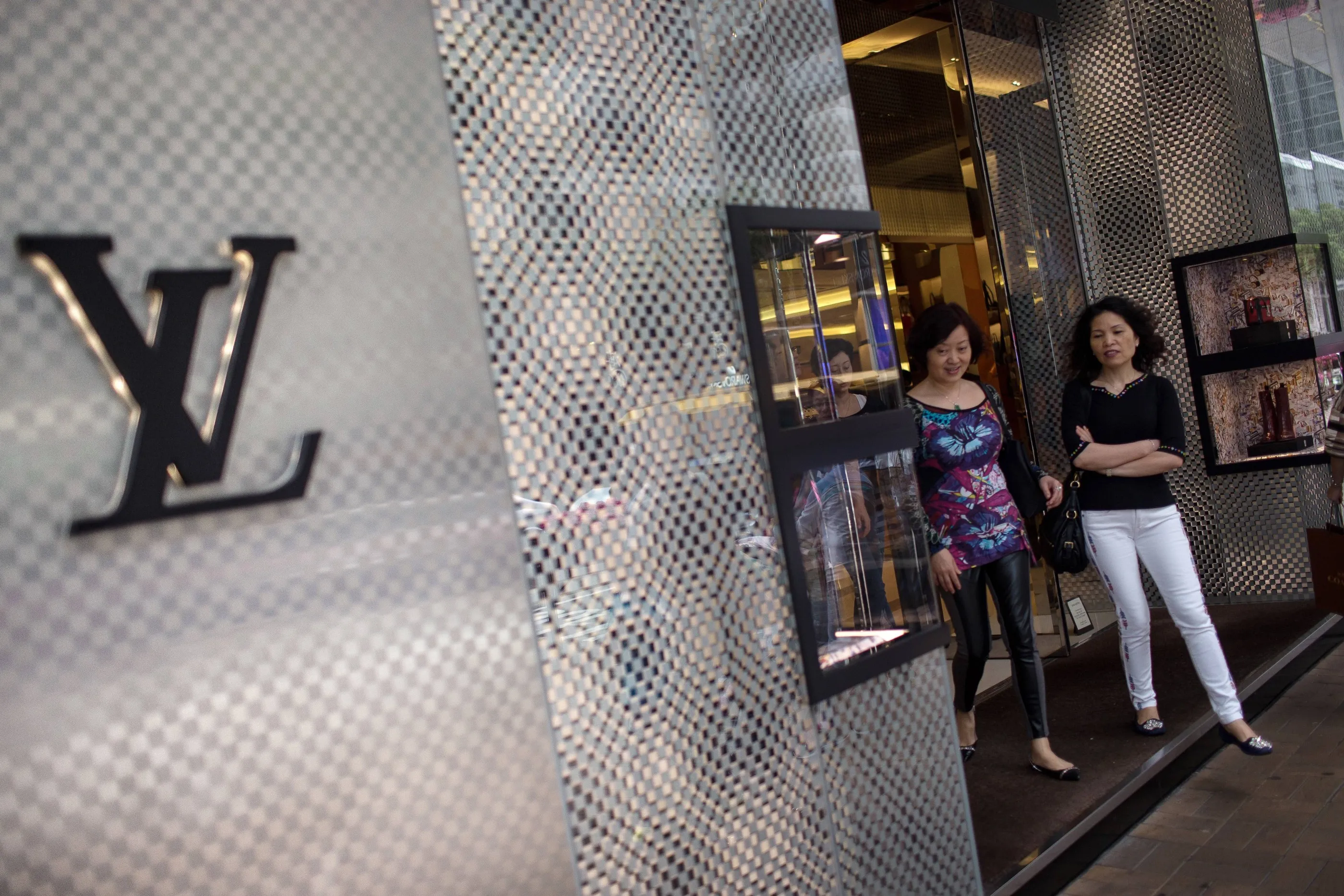 Shoppers exit a Louis Vuitton store, operated by LVMH Moet Hennessy Louis Vuitton SA, on Canton Road in the Tsim Sha Tsui area of Hong Kong, China, on Saturday, April 18, 2015. Hong Kong is scheduled to release consumer price index (CPI) figures on April 21.
