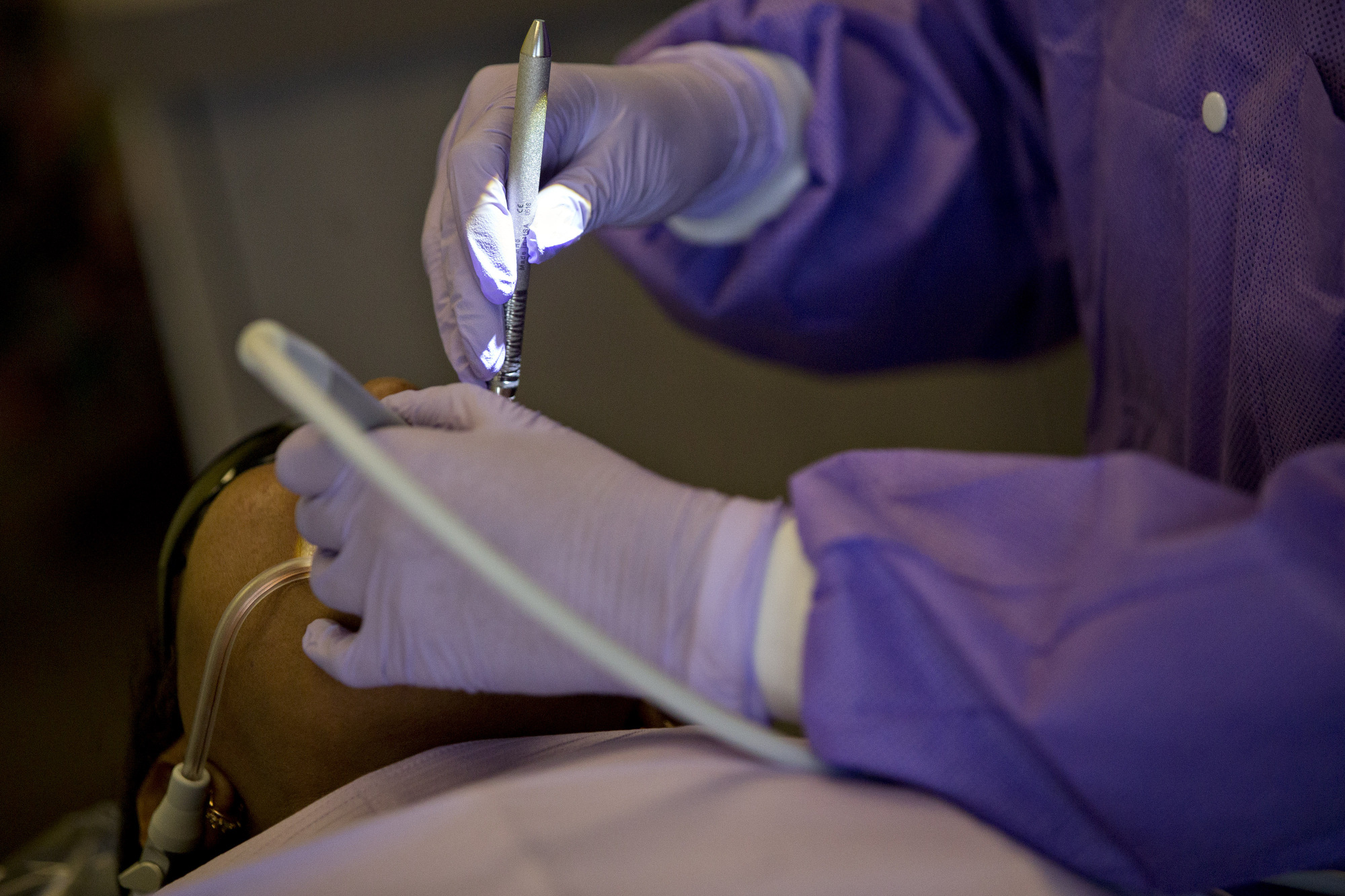 A dental hygienist cleans the gums of a patient.
