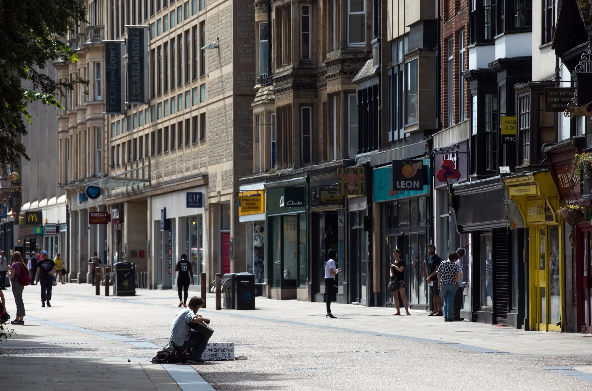 A busker plays a guitar on a pedestrianised shopping precinct in Oxford.