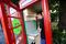 Alex Perjescu, co-founder and chief technical officer of Lovefone, applies decals to a phone box during the installation of a Lovefone, an electronics repair shop, outlet on Greenwich High Road, in London, U.K., on Monday, Aug. 15, 2016. The U.K.'s iconic red phone booths are being adopted and re-used as businesses and nonprofits throughout the country. Photographer: Simon Dawson/Bloomberg