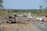 Debris and destroyed cars are seen along the street in