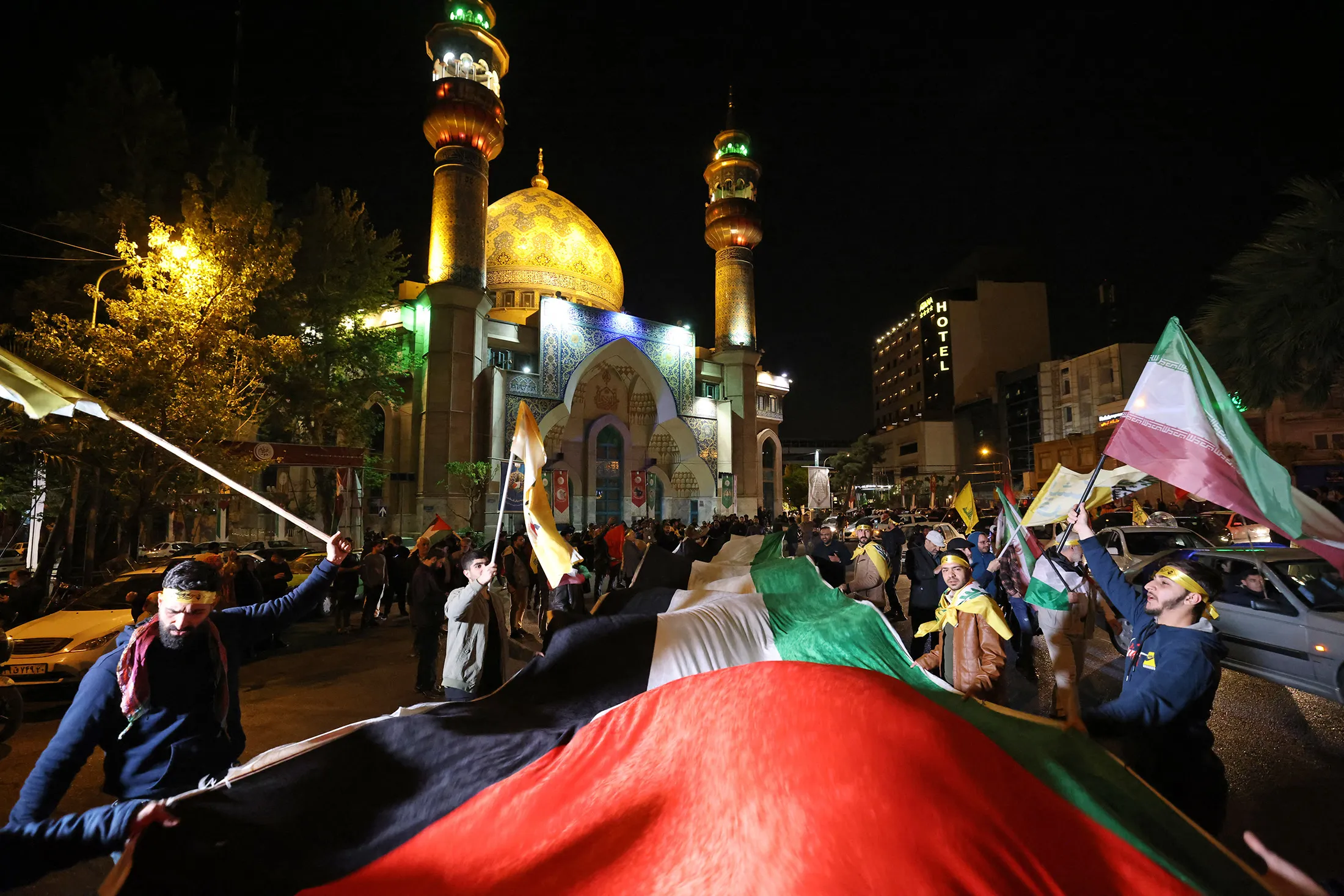 Demonstrators wave Iranian and Palestinian flags to celebrate the launch of a drone and missile attack on Israel, at Palestine Square in Tehran on April 14.