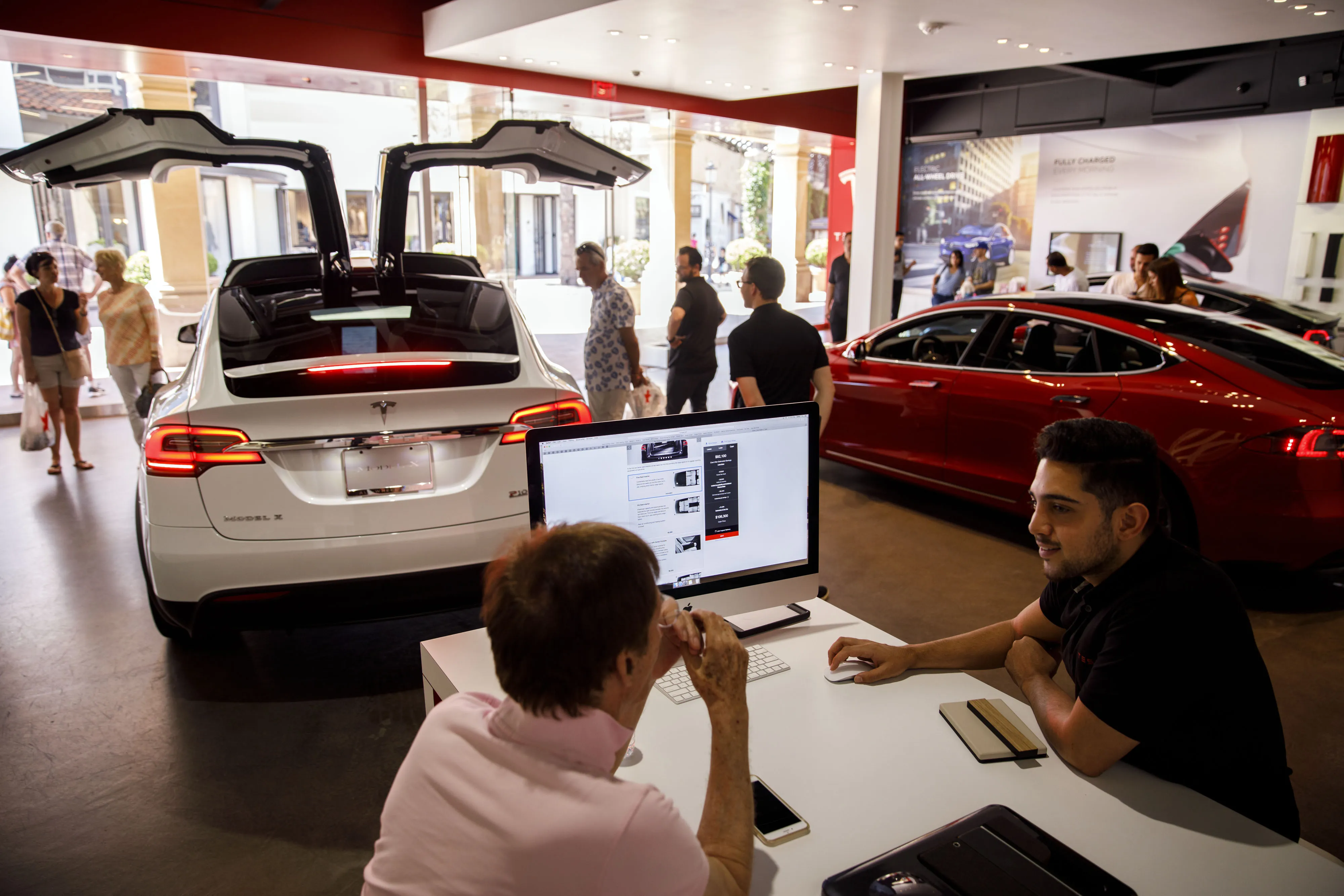 An employee speaks with a customer at a Tesla showroom.